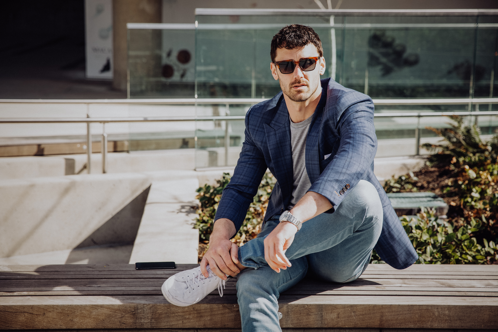 Stylish tall arabian man model in white shirt, jeans and sunglasses sitting  at street of city. Beard attractive arab guy at park. 10473032 Stock Photo  at Vecteezy