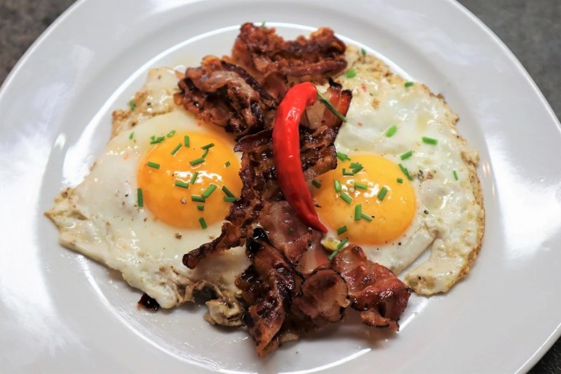 Bacon and eggs on a white plate.