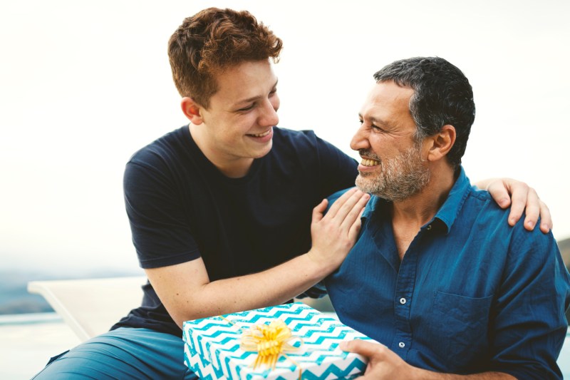 A father happily holding the gift his son gave in the outdoors.