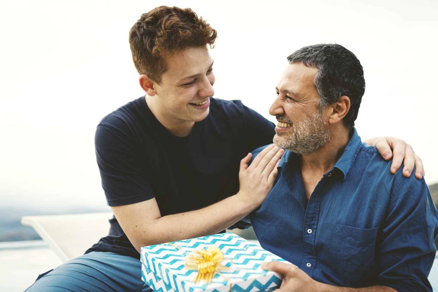 A father happily holding the gift his son gave in the outdoors.