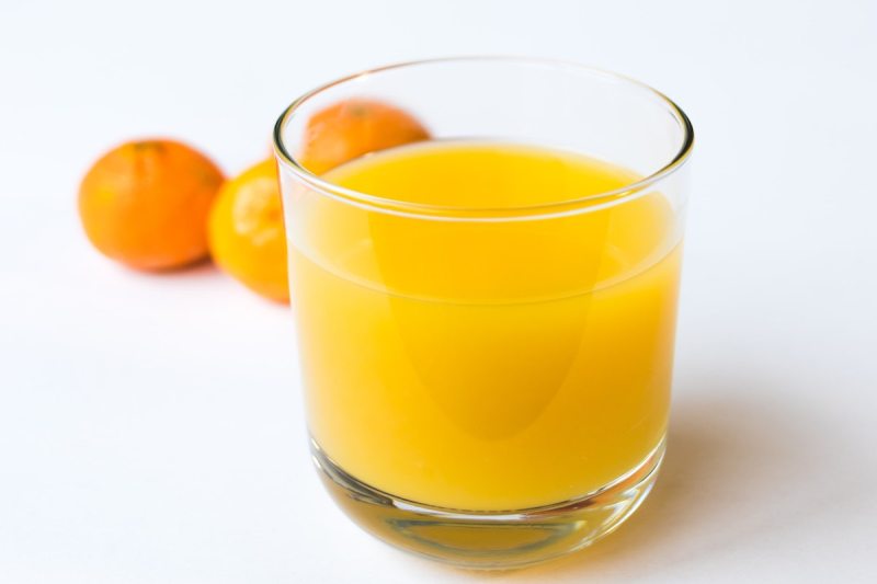 Glass of orange juice with oranges in the background