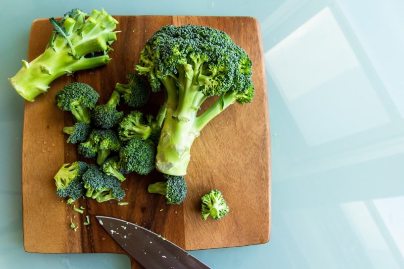 Broccoli stalk, florets, and broccoli head on a cutting board.