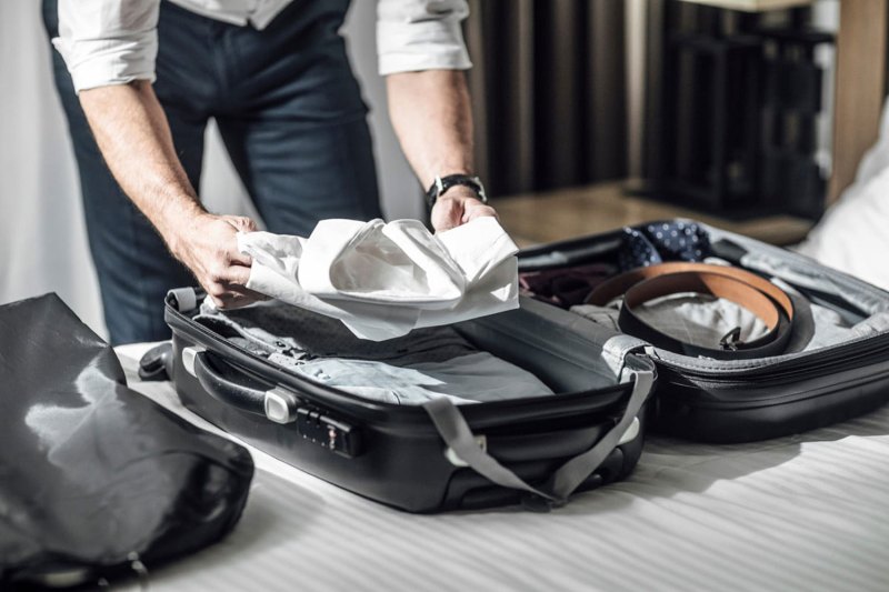Man packing clothes into a suitcase.
