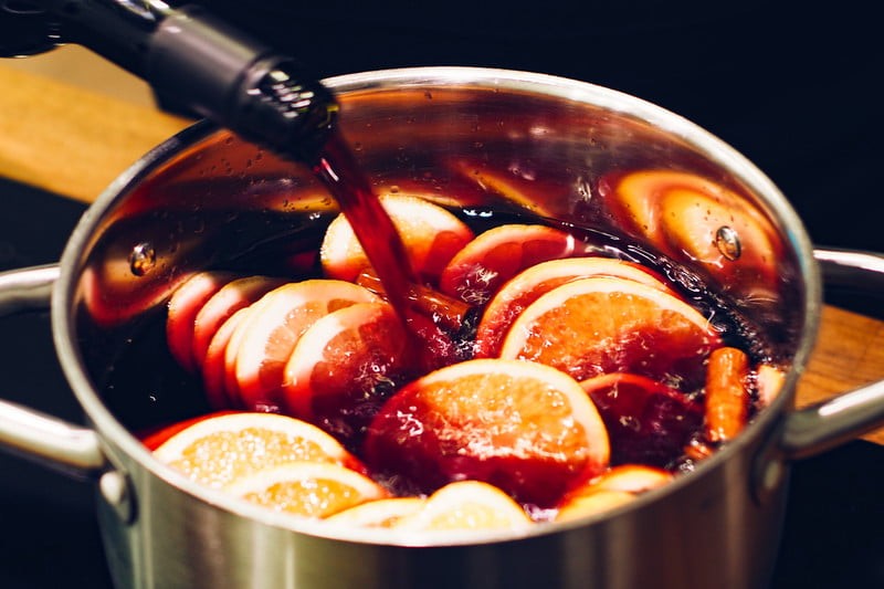 Fruit and spices in a stockpot being filled with wine