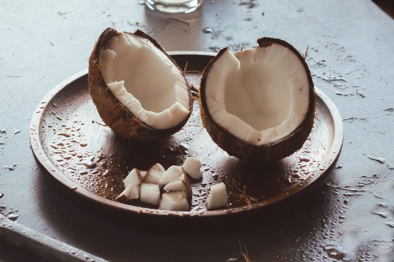 Cracked coconut served on a wooden plate.