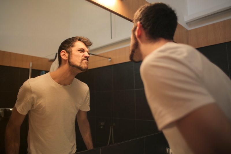 Man critiquing his jaw in a mirror.