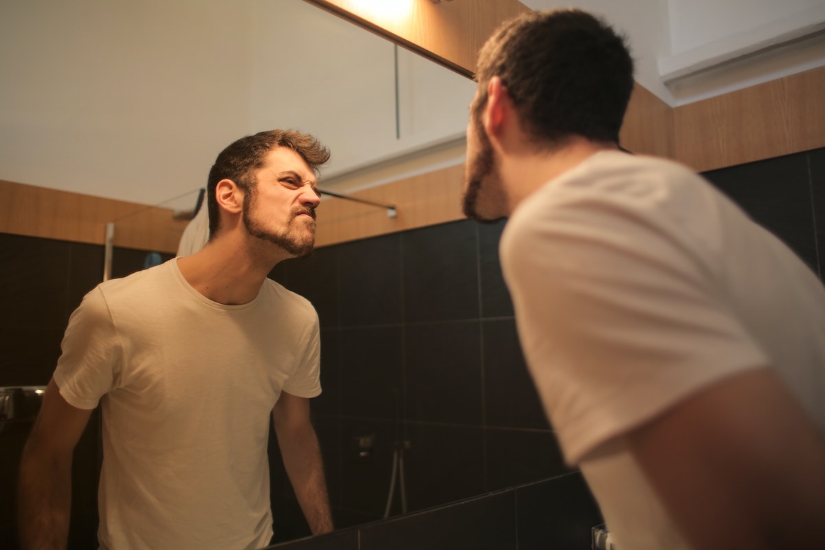 Man critiquing his jaw in a mirror.