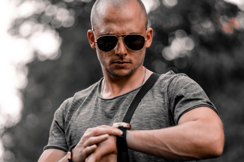 Man checking tactical watch on a stylized grey background.