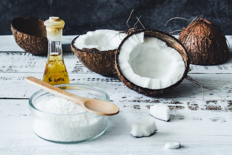 coconut cut in half with shredded coconut and oil.