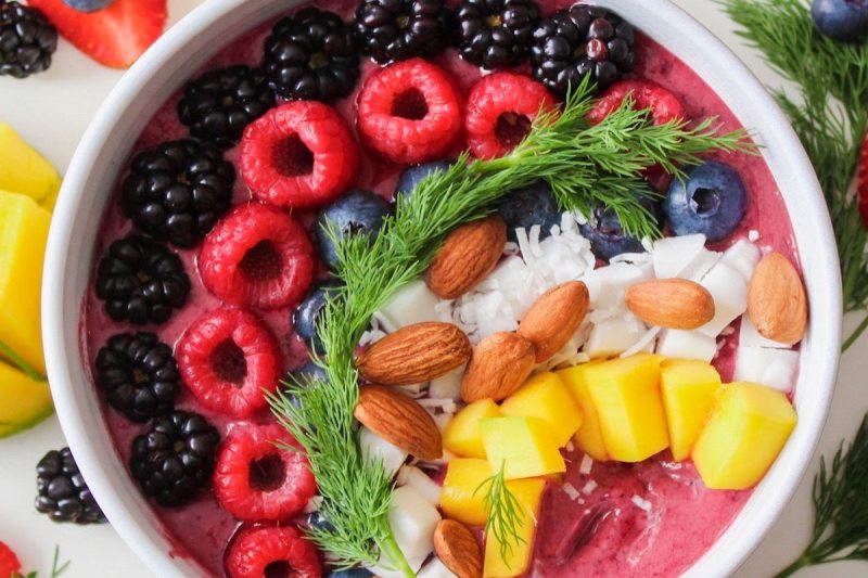 A bowl of fruit including raspberries and pineapple.