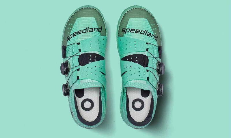 a pair of teal speedland running shoes against a teal background.