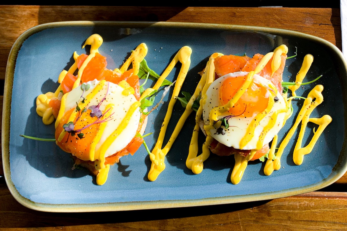 Two fried eggs and salmon served on a blue oval plate.