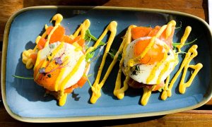 Two fried eggs and salmon served on a blue oval plate.