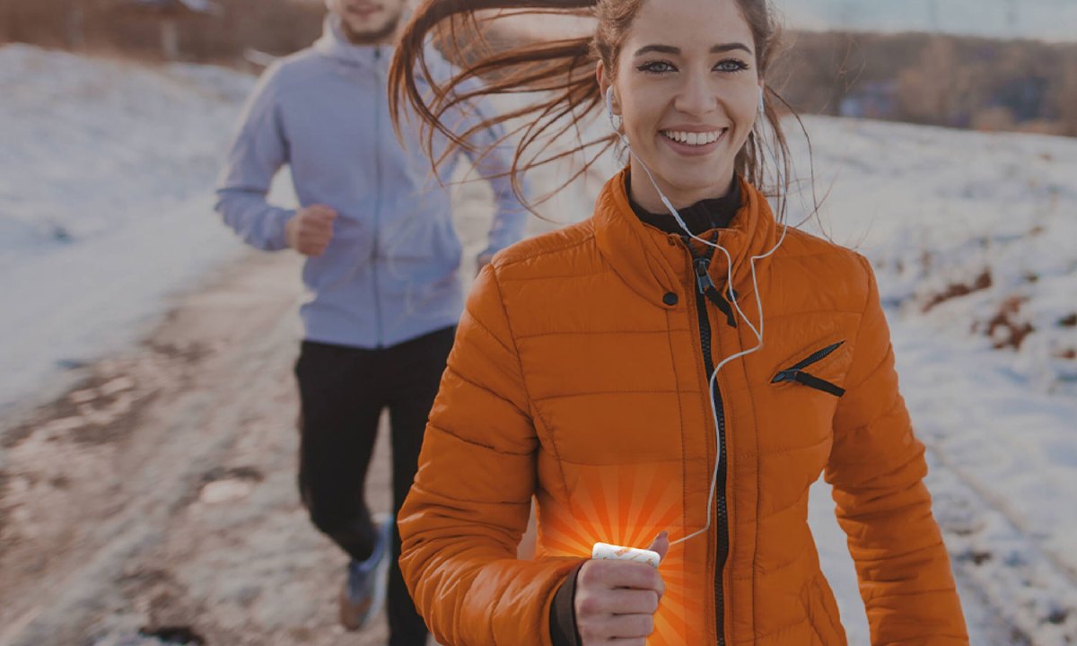 Woman jogging in winter holding a chemical hand warmer.