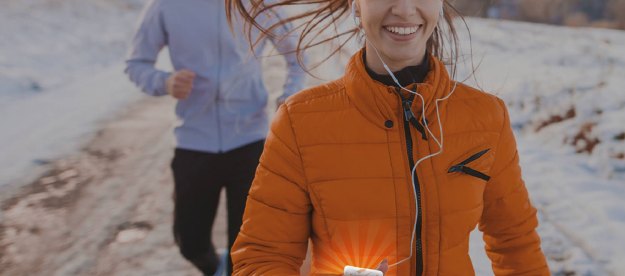 Woman jogging in winter holding a chemical hand warmer.