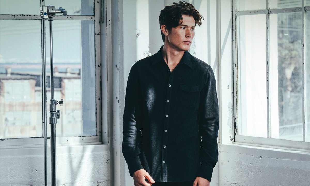 Man standing in loft space wearing Mission Workship's The Nash gray shirt-jacket.