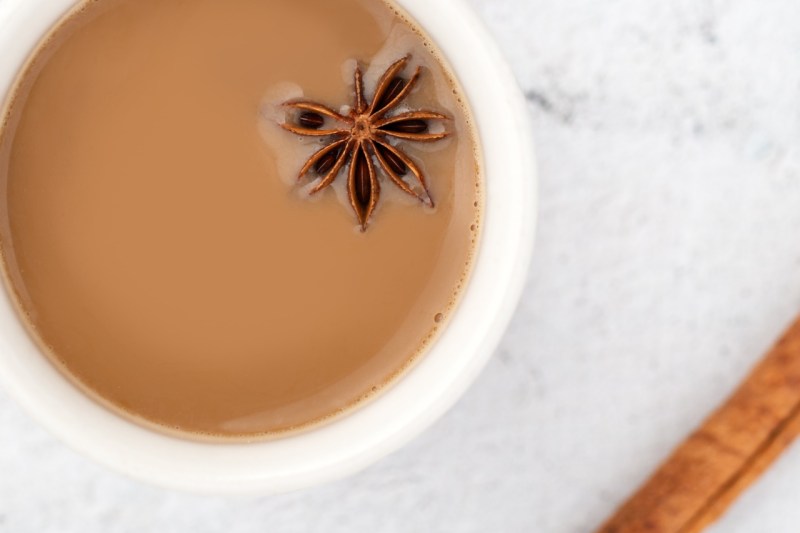 Indian chai in a white cup with floating star anise.