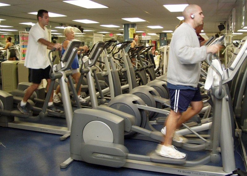 Men using elliptical trainers in the gym.