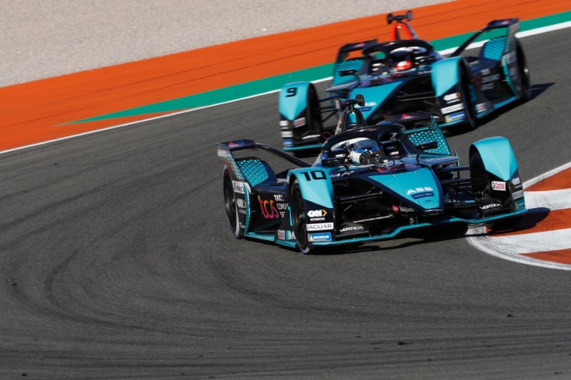 Two formula e race cars on the track.