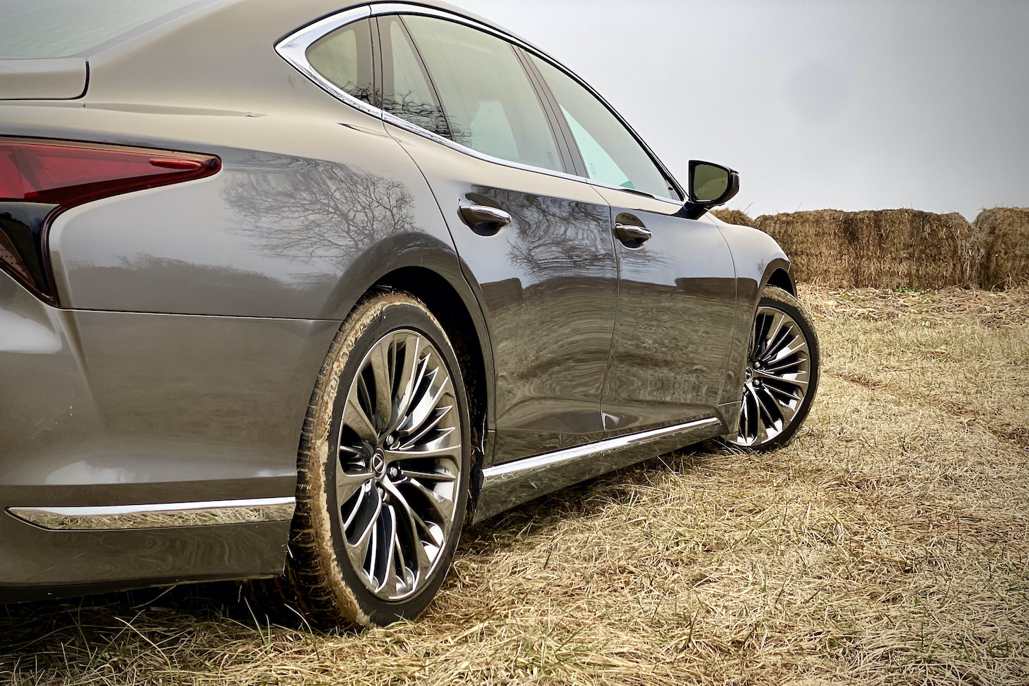 The wheels on the 2021 Lexus LS500 from the side in a grassy field.