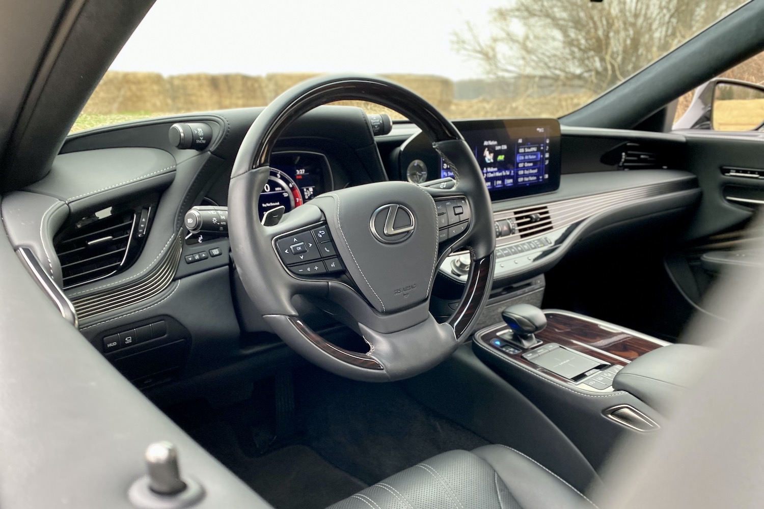 A close-up of the 2021 Lexus LS500's rear end in a grassy field with hay bales in the back.