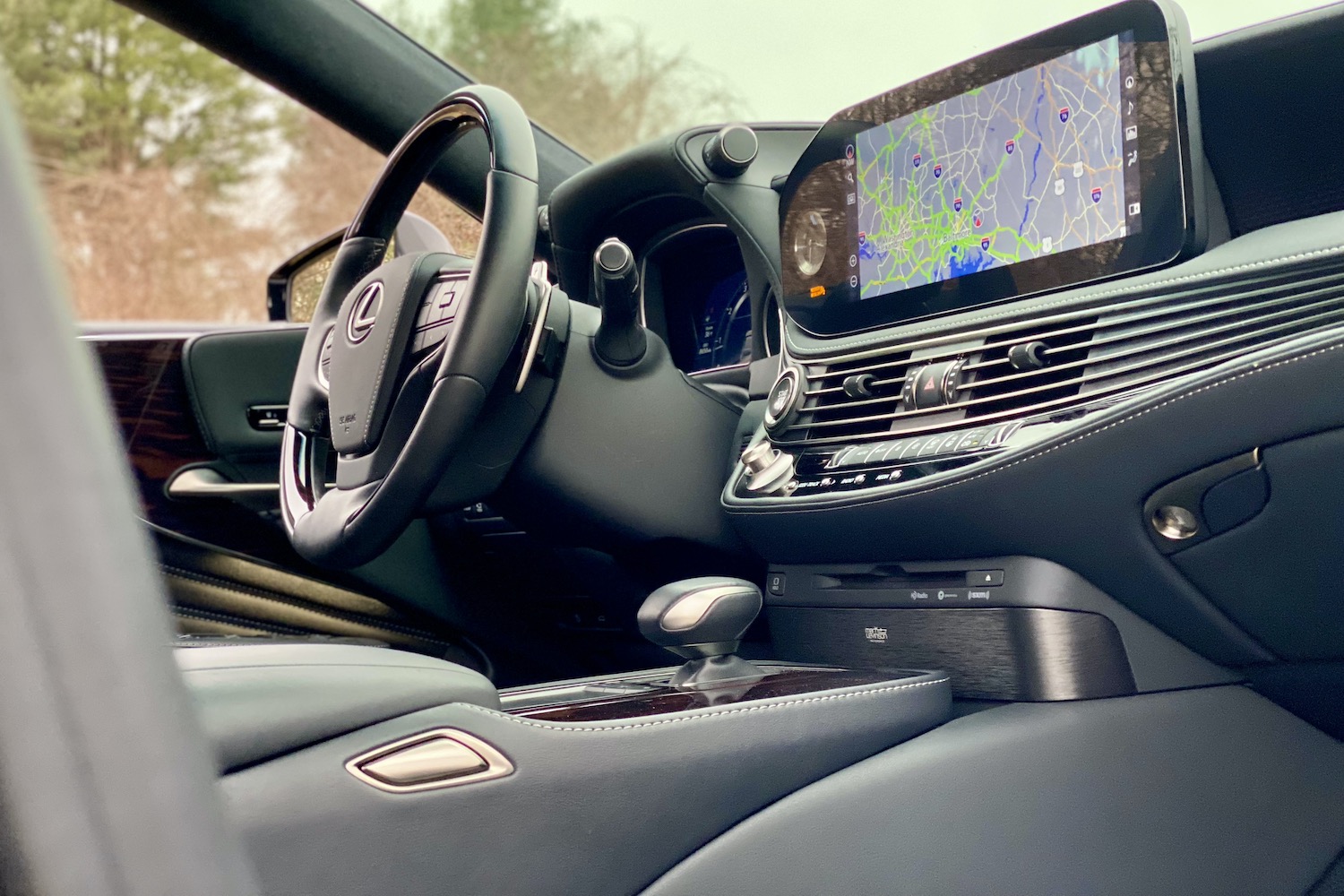 The 2021 Lexus LS500's center console from passenger's door with trees in the back.