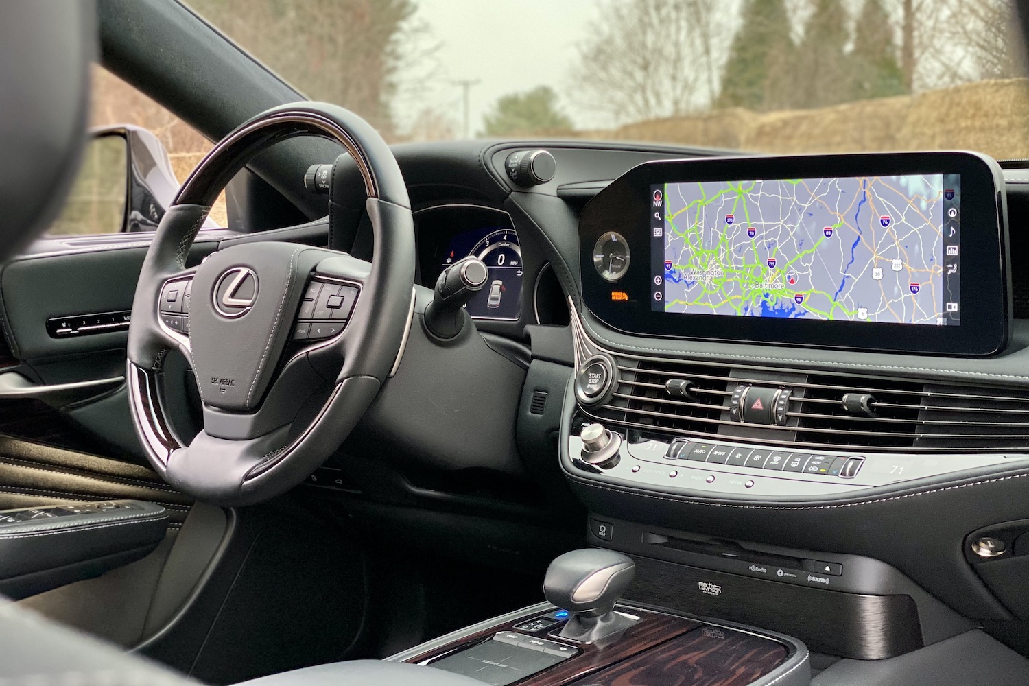 The 2021 Lexus LS500's center console and steering wheel from rear seats with trees in the back.