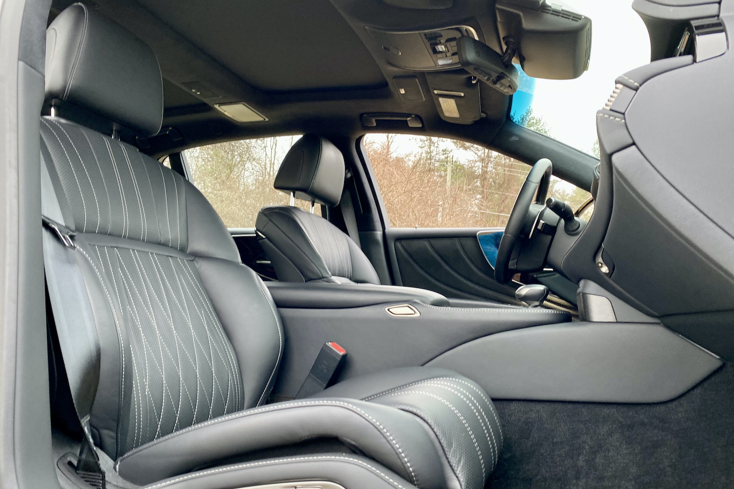 The front passenger seat in the 2021 Lexus LS500 from outside with trees in the back.