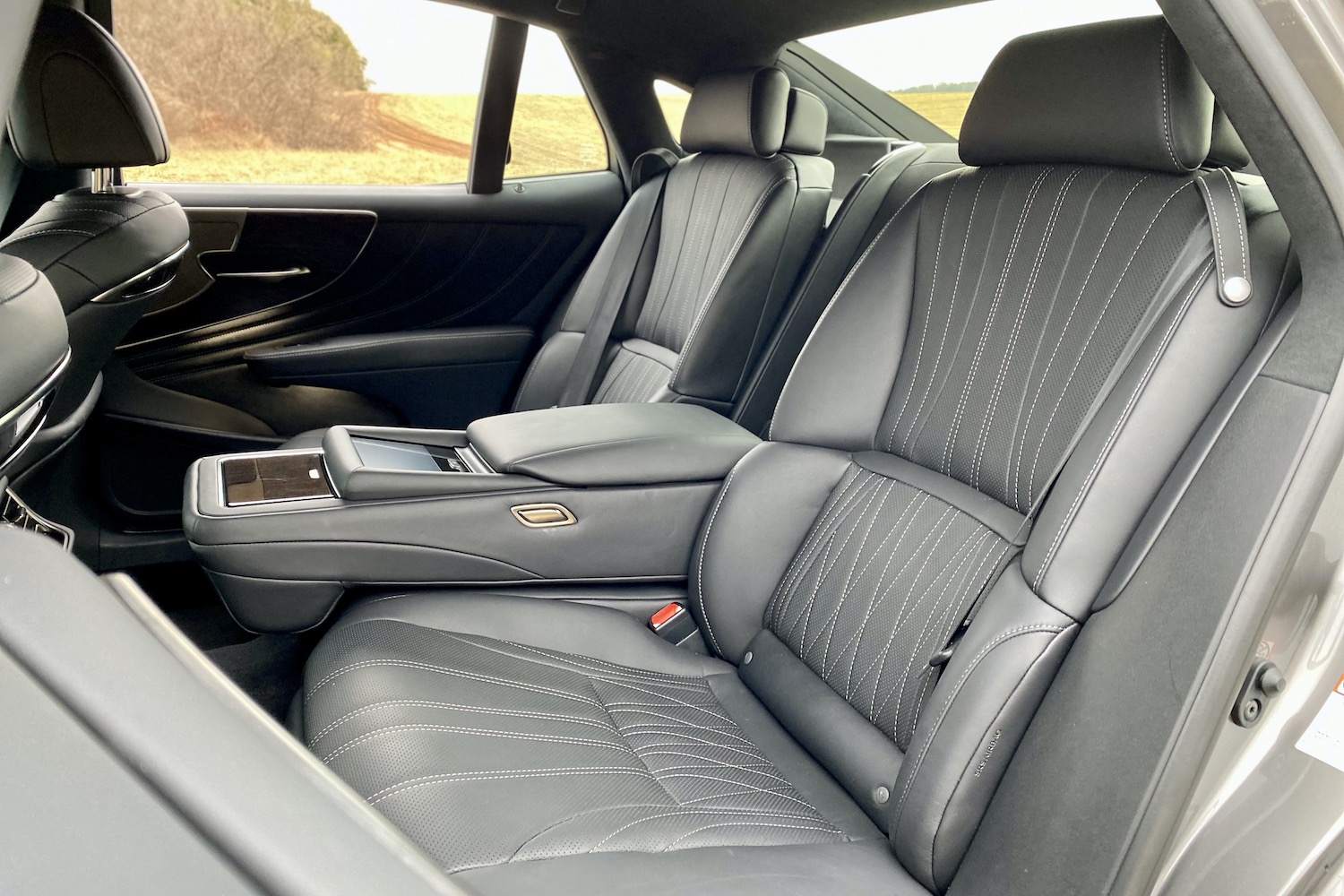 The rear seats in the 2021 Lexus LS500 from outside with trees in the back.