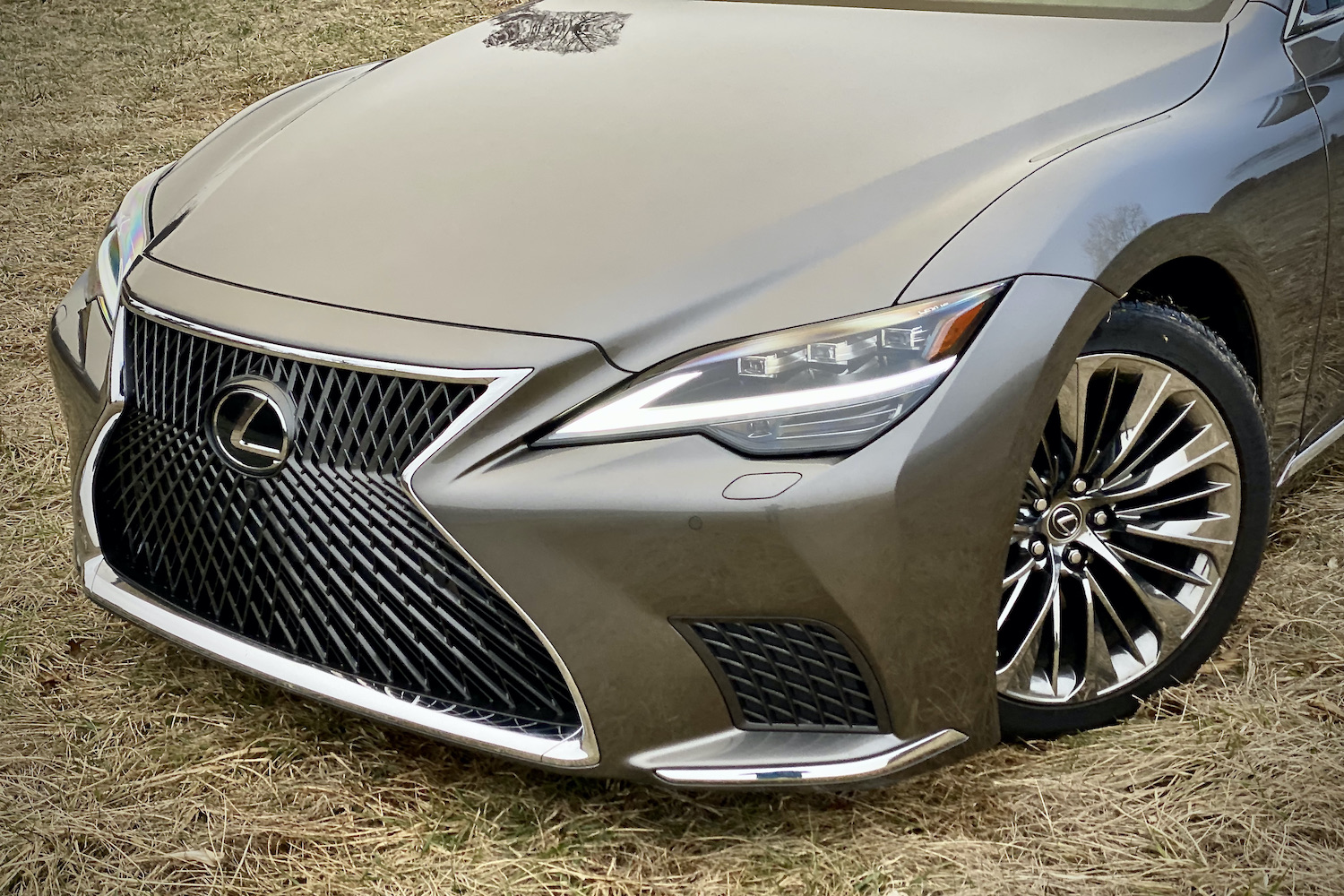 A close-up of the front end of the 2021 Lexus LS500 from driver's side on a grassy field.