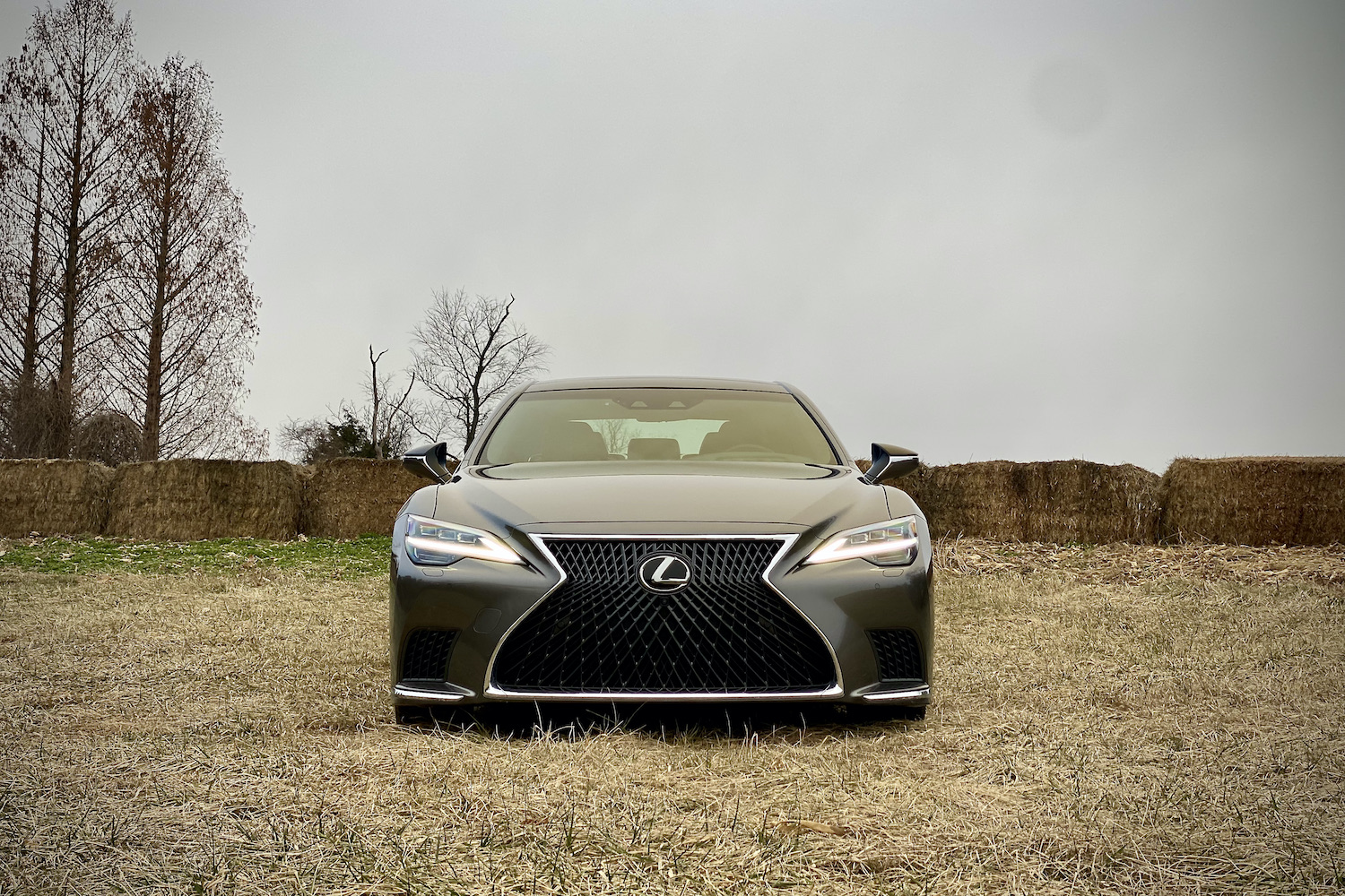 The front end of the 2021 Lexus LS500 in a field in front of hay bales.