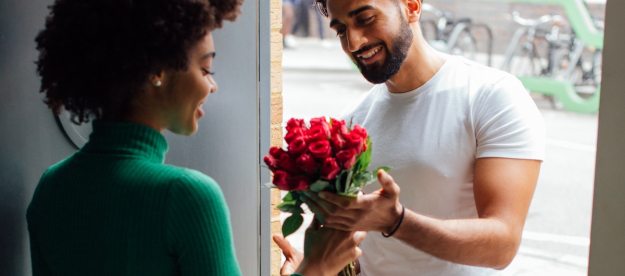 Man giving woman a bouquet or red roses.