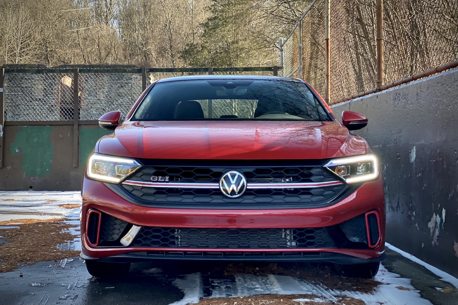 Close up of 2022 Volkswagen Jetta front end with headlights on in a snow covered parking lot.