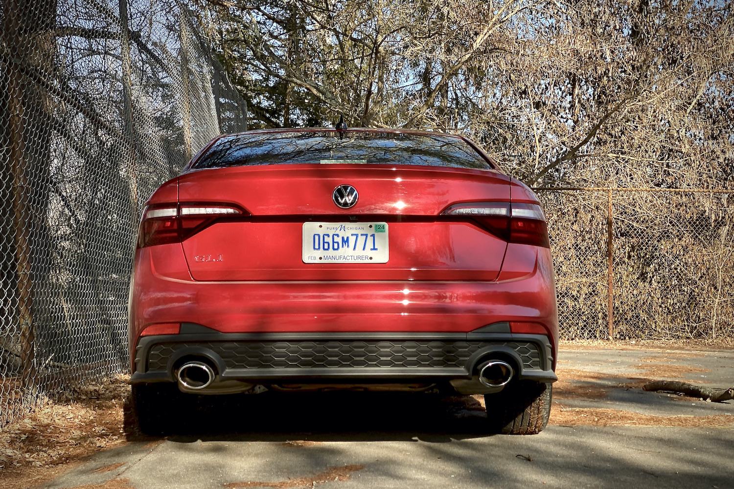 Close up of 2022 Volkswagen Jetta rear end on a concrete parking lot with trees in the background.