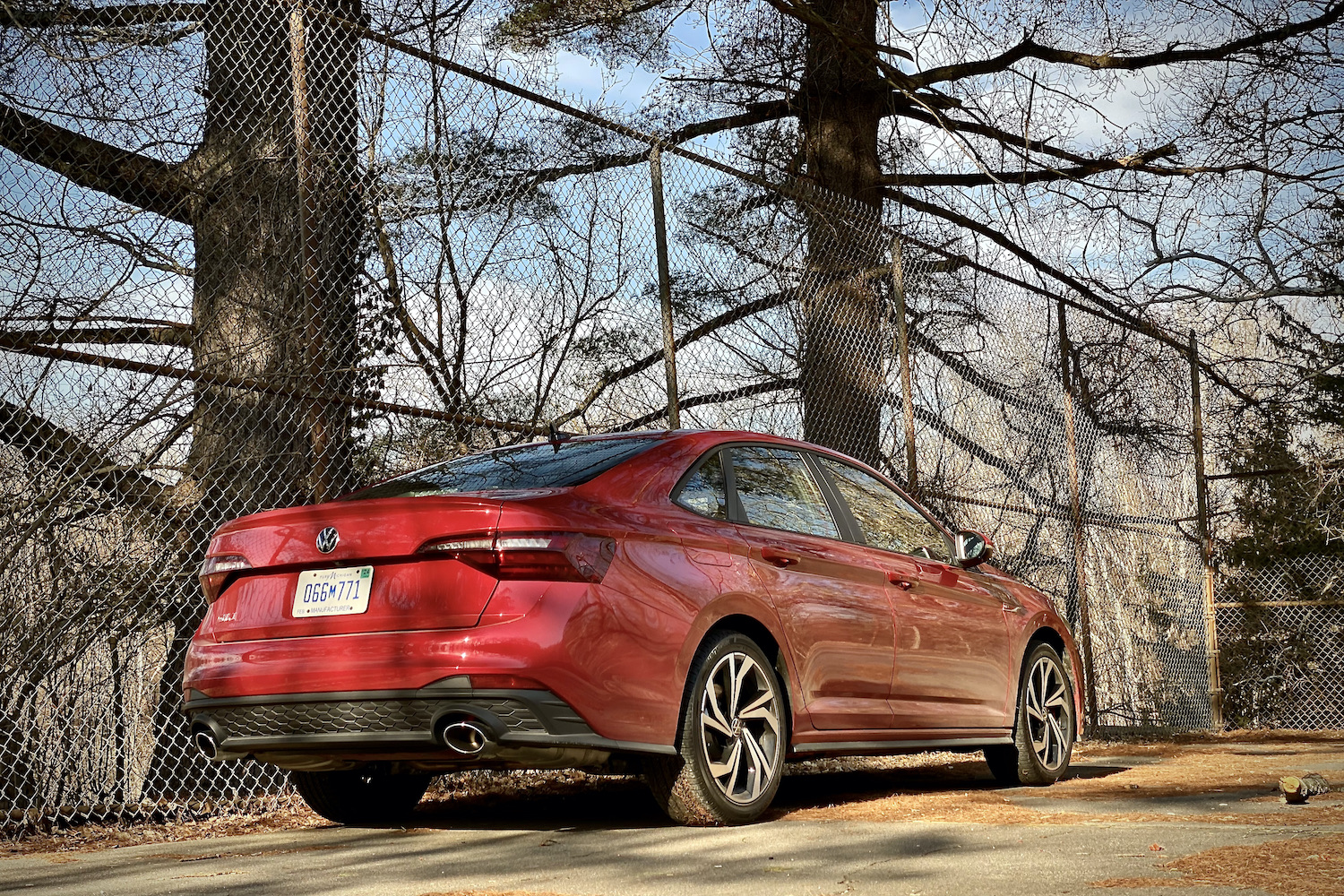 Side profile of 2022 Volkswagen Jetta GLI in a parking lot in front of trees.