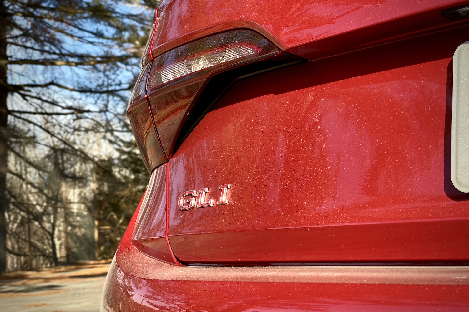 Close up of 2022 Volkswagen Jetta GLI rear badge with trees in the back.