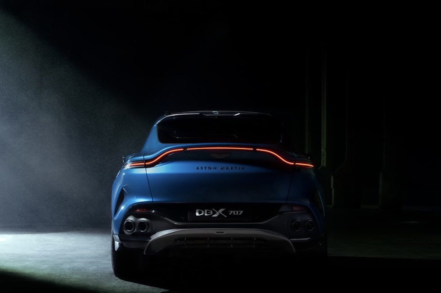 Rear end of Aston Martin DBX 707 in a dark warehouse.