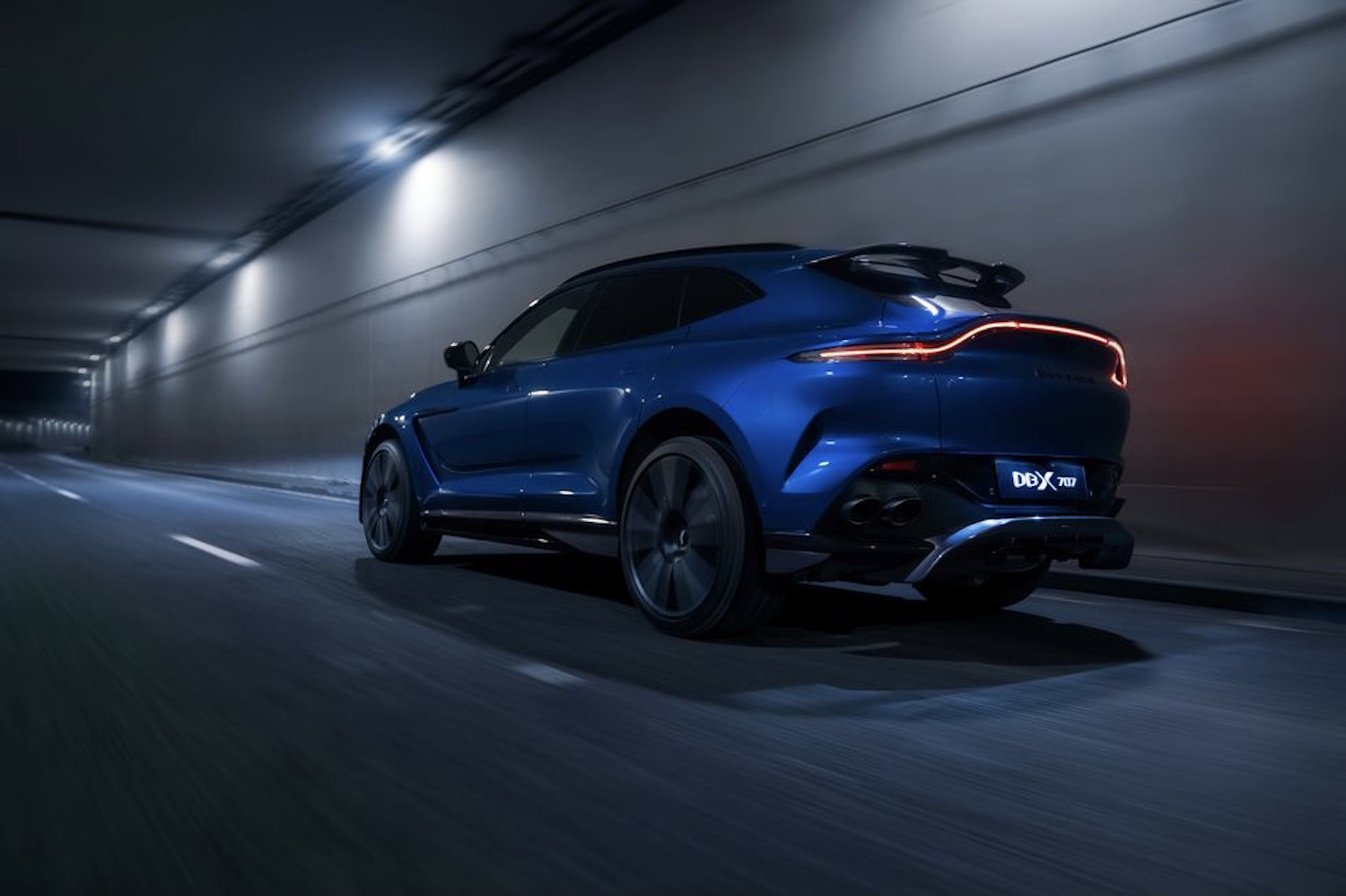 Rear end angle of Aston Martin DBX 707 driving in a dark tunnel.