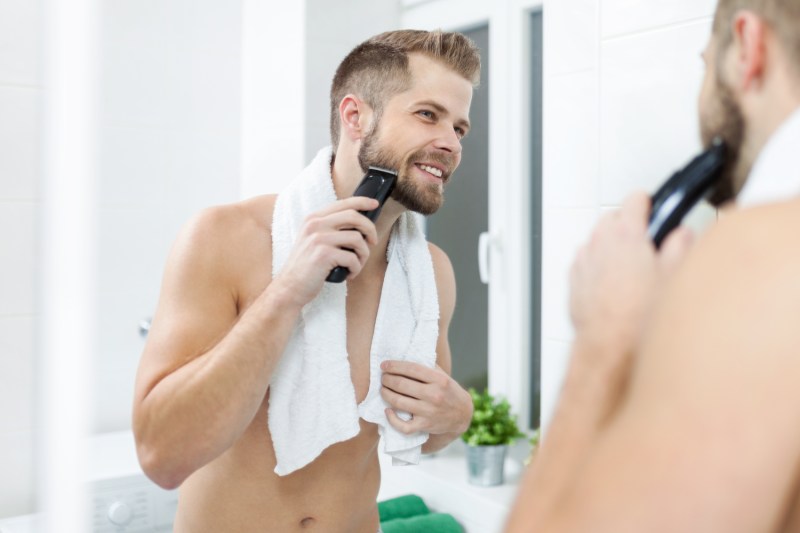 Man grooming and trimming his facial hair with a beard trimmer