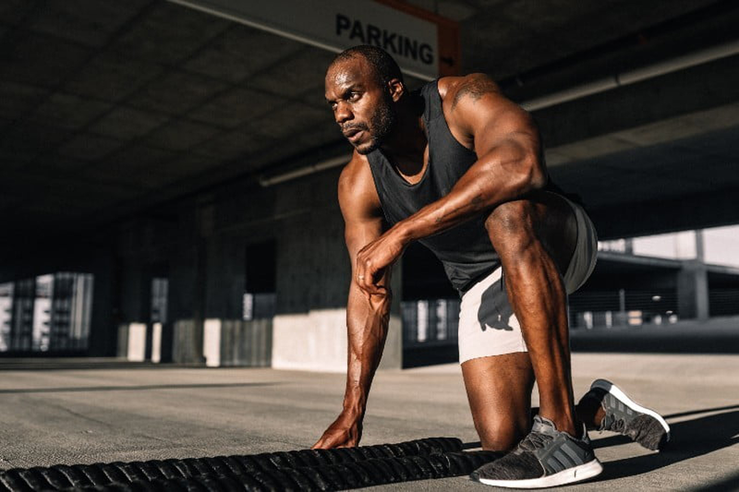 A man bending down on one knee in the middle of a workout.