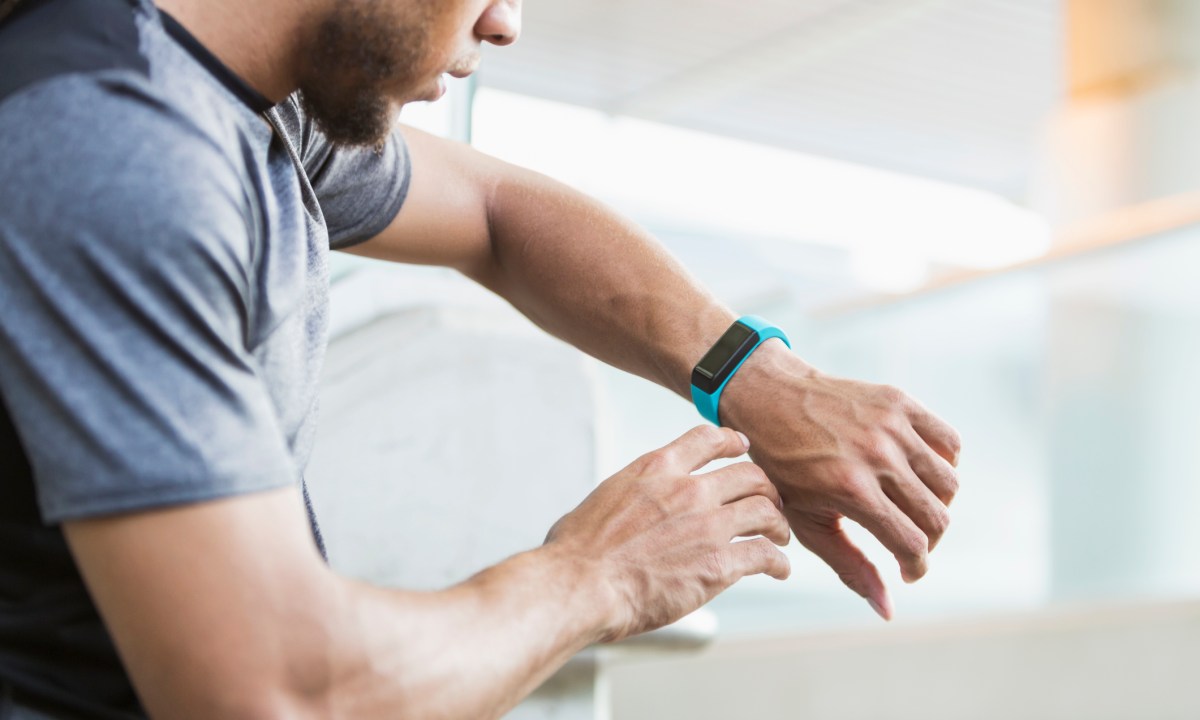 Young mixed race man checking his fitness tracker.