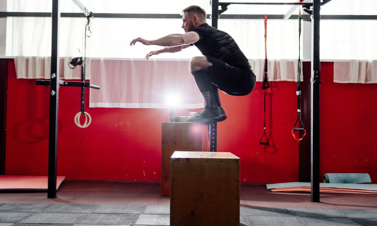 A man doing a box jump in a gym