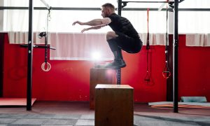 A man doing a box jump in a gym