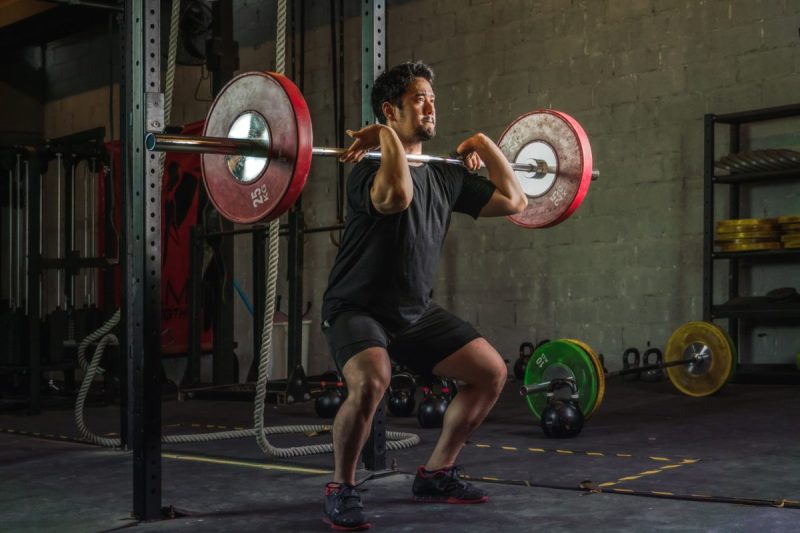 A man doing a front squat with a barbell.