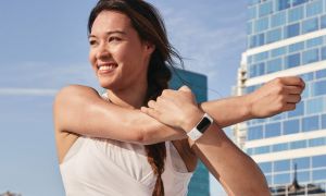 Woman stretching while wearing Fitbit Charge 5.