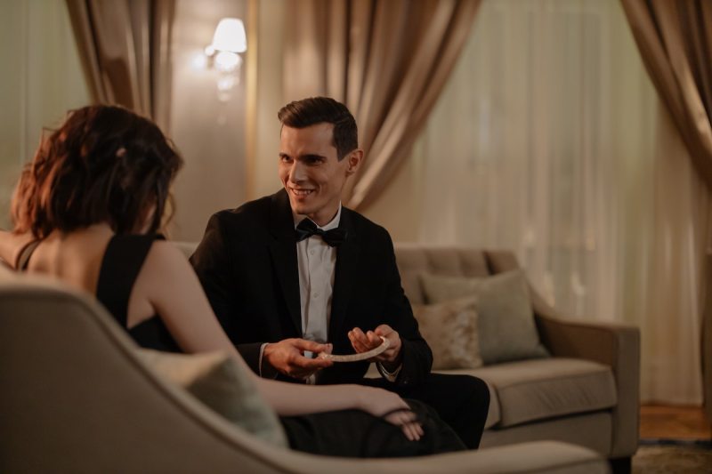 Man in tux giving girlfriend a gift.