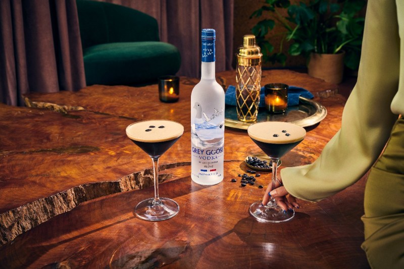 Two espresso martinis sitting next to a bottle of grey goose.