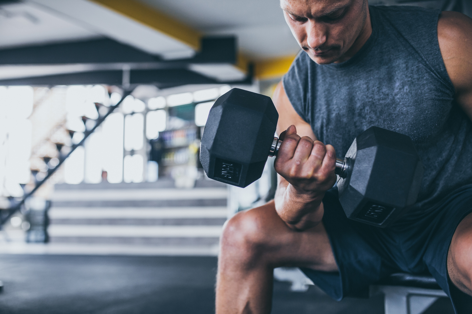 A male athlete lifting a dumbbell in a gym.