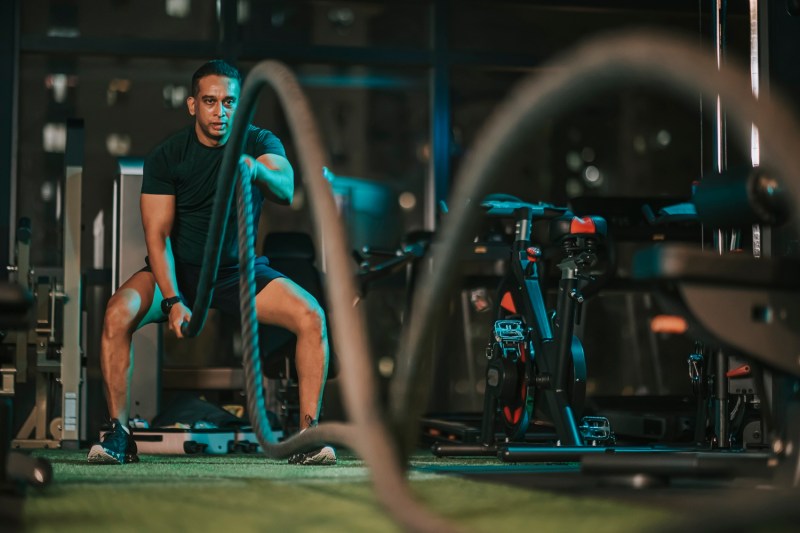 A man using battle ropes in a gym