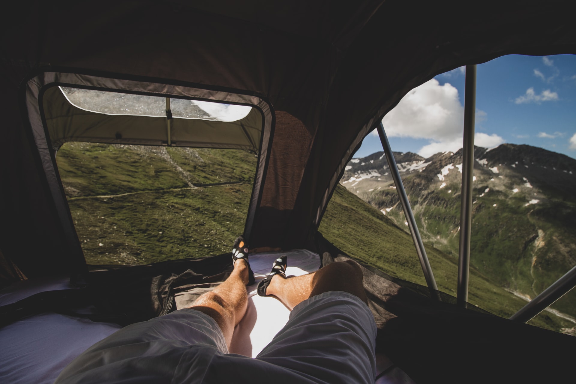 Man solo camping in a rooftop tent in the mountains.